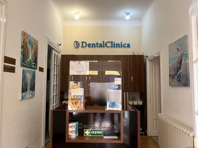Recepția DentalClinica, cu numele clinicii pe perete și tablouri