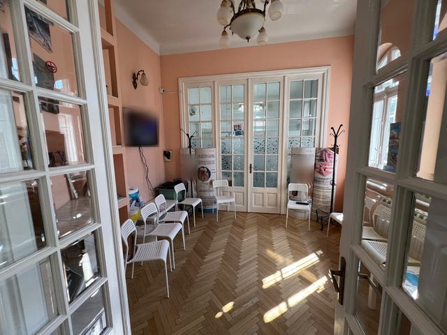 Sala de așteptare DentalClinica: pereți în nuanțe calde, candelabru, parchet în spic și uși albe cu geam